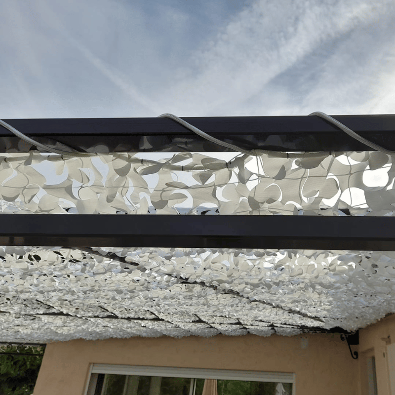 Corde en polyester tressé fixant un filet de camouflage blanc sur une pergola