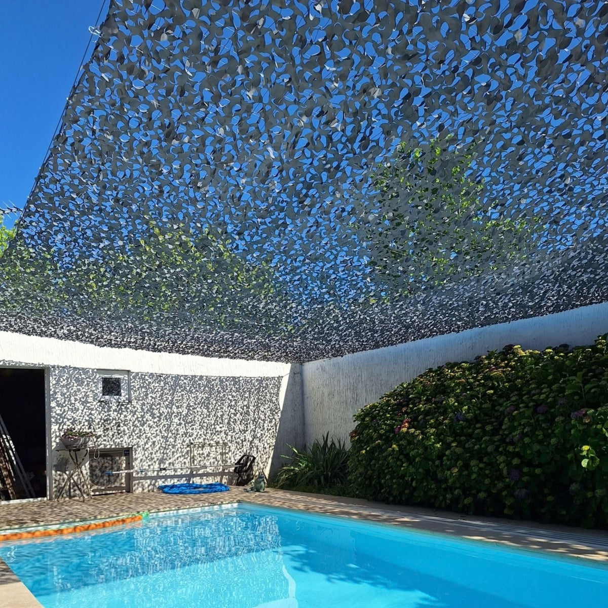 Filet de camouflage gris couvrant un patio avec piscine