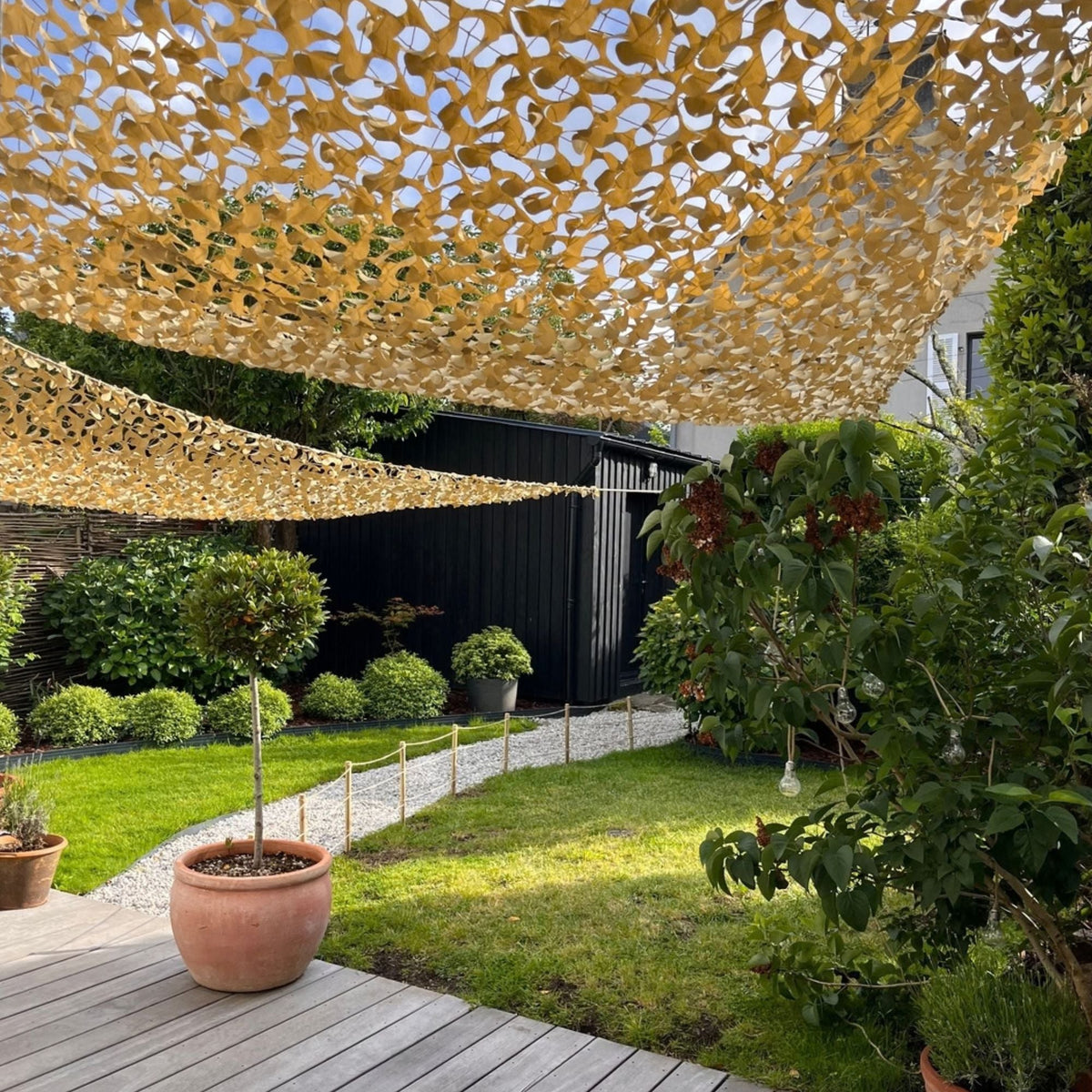 Filets de camouflage triangulaires beiges en voiles d'ombrage dans un jardin