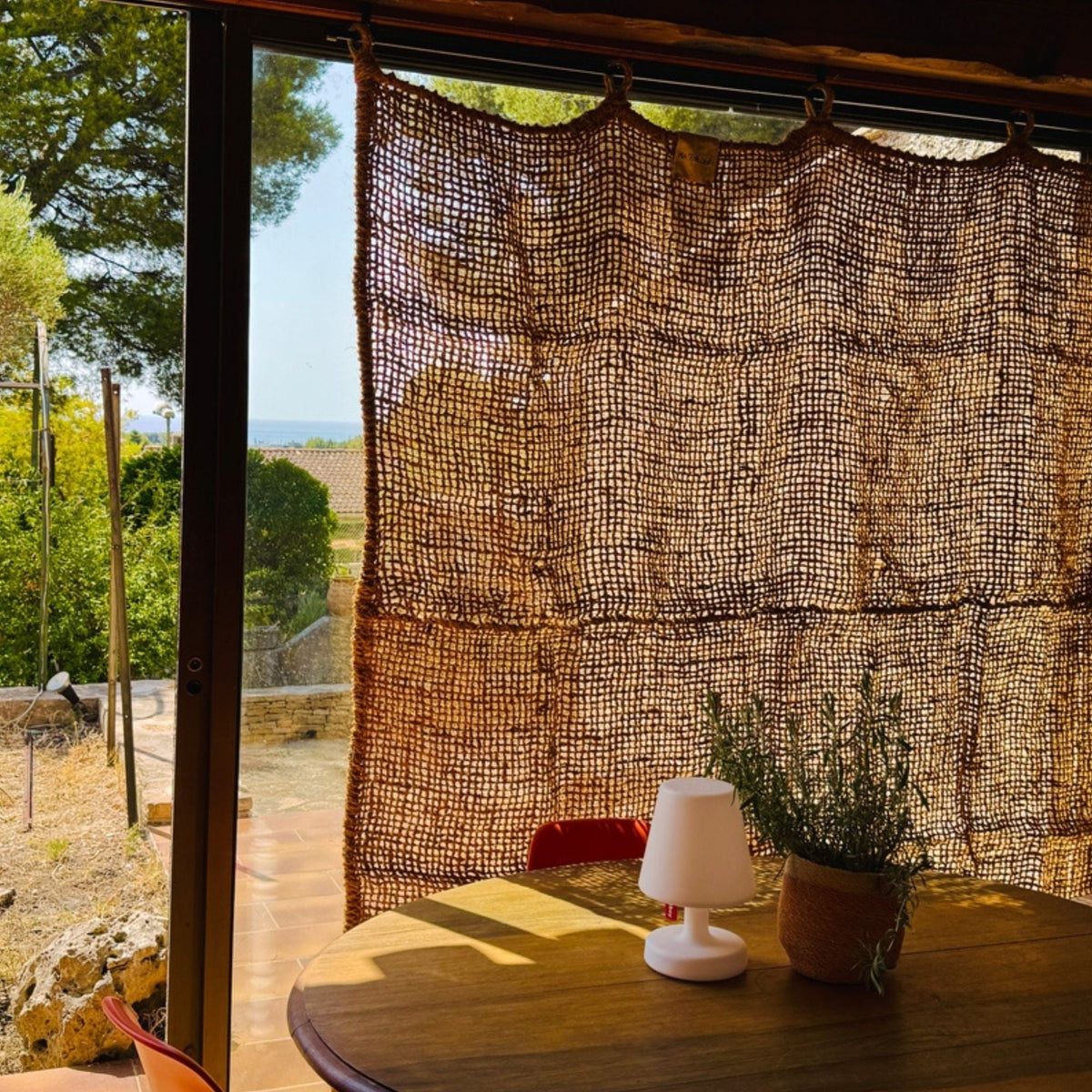 Rideau en fibre de coco près d'une fenêtre avec table et lampe