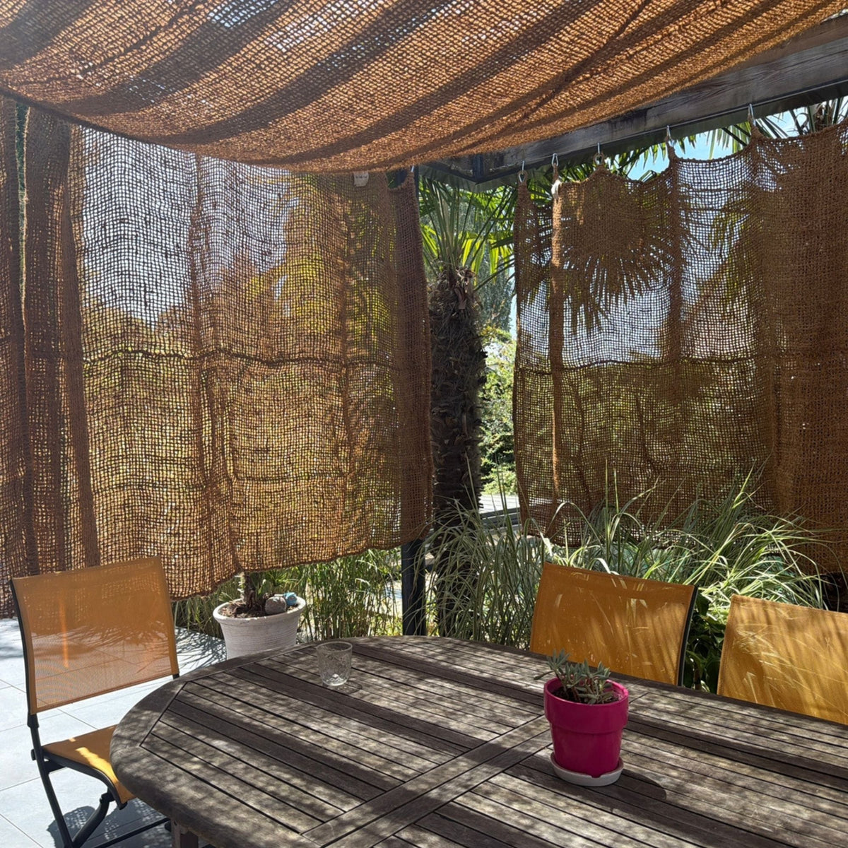 Rideaux en fibre de coco servant de clôture à une terrasse avec pergola