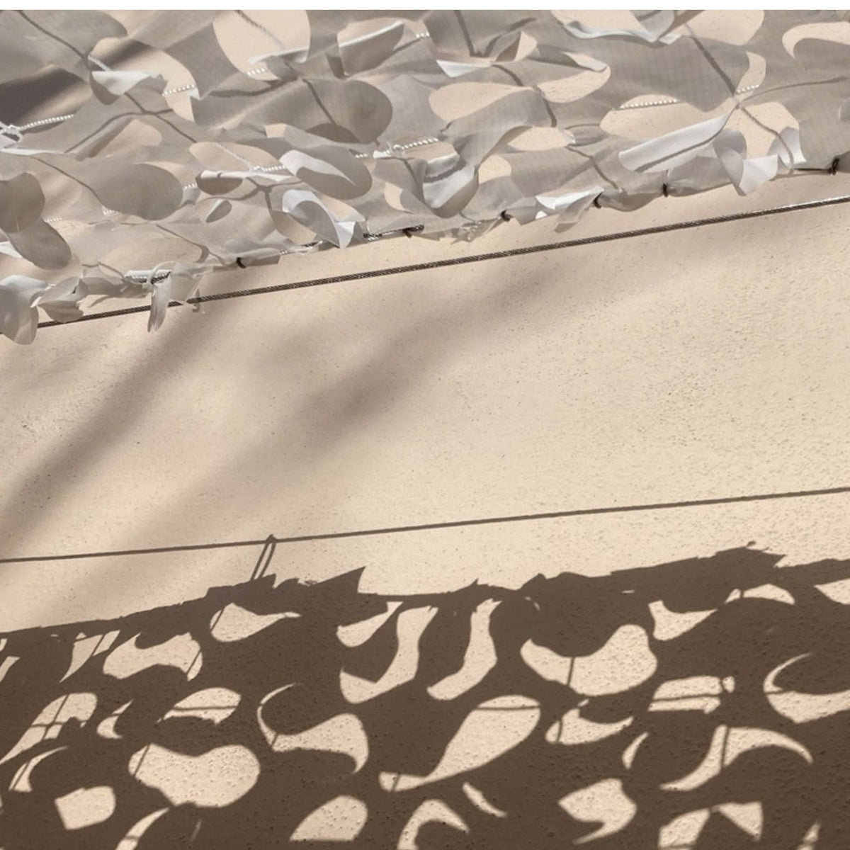 Câble acier tendu avec filet de camouflage blanc et son ombre sur un mur