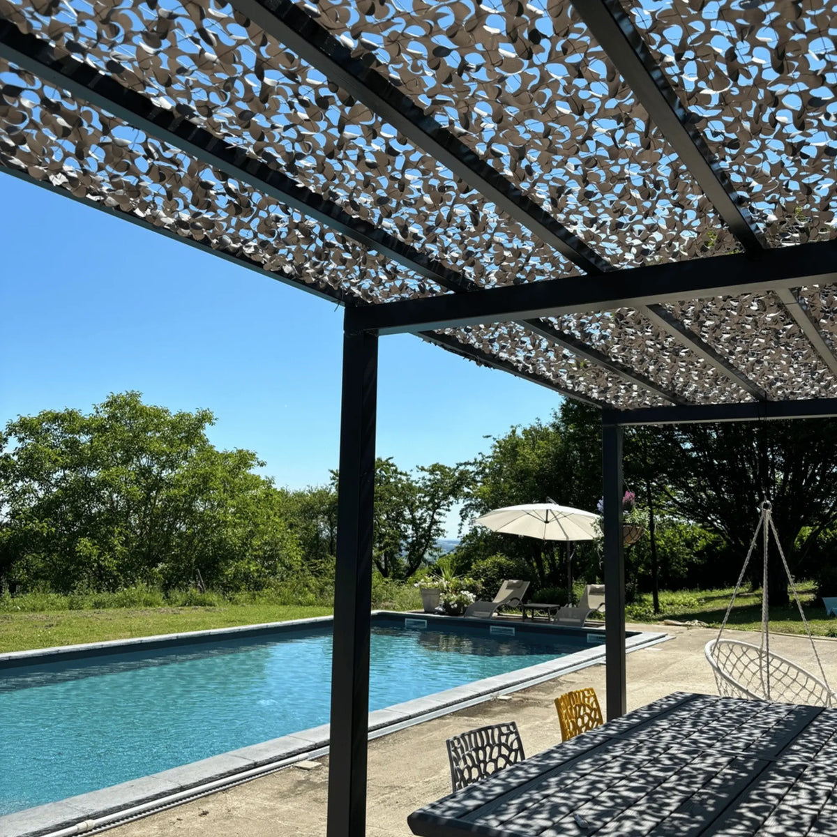 Filet de camouflage renforcé gris sur une pergola au bord de la piscine